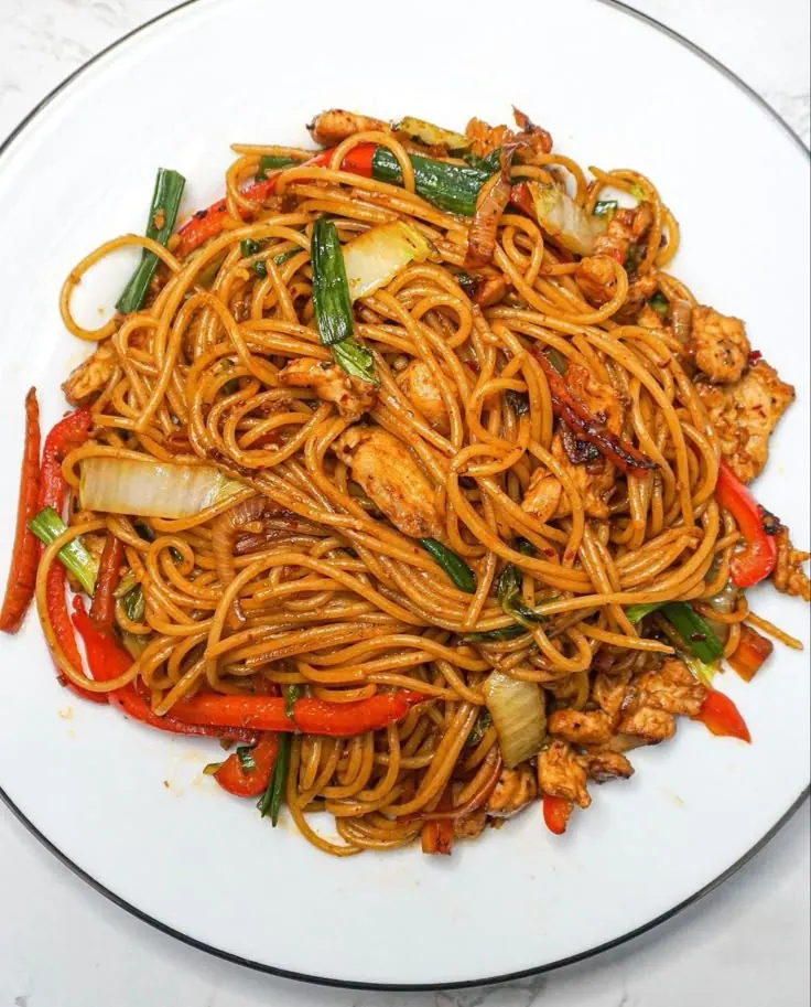 Jollof spaghetti tossed with peppers and spring onion