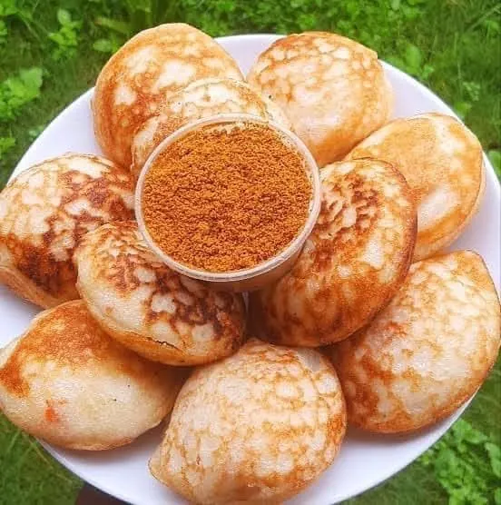 A platter of masa rice cakes arranged around a bowl of suya spice