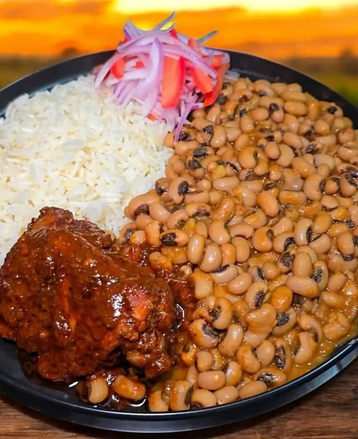 Rice and beans with plantain and stewed chicken on a sizzling platter